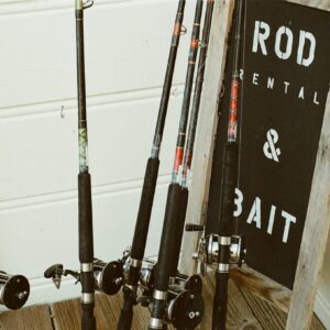 Collection of fishing rods beside a bait rental sign outdoors.