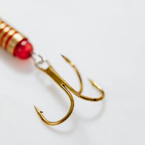 Detailed view of a golden fishing hook with bait on white background.