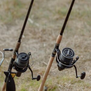 Detailed view of fishing rods with reels set up on grassy terrain, ideal for outdoor angling activities.